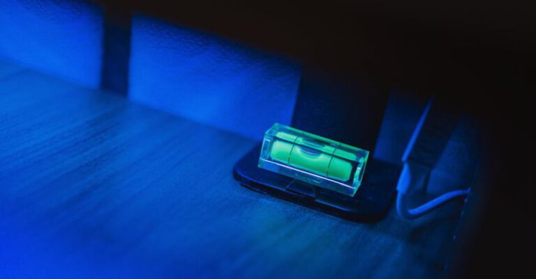 Evaluate - Small illuminating green neon bubble level placed on monitor stand in dark room