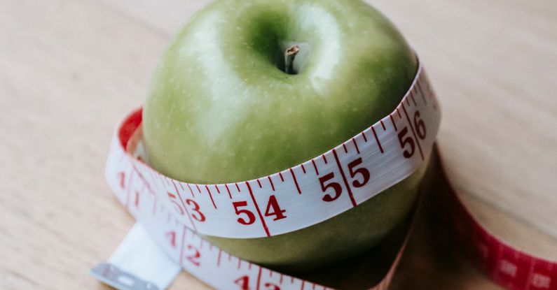 High-Quality Tape - Green apple with measuring tape on table in kitchen