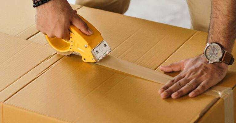 Custom Tape - Unrecognizable man sealing box with duck tape while preparing for moving out