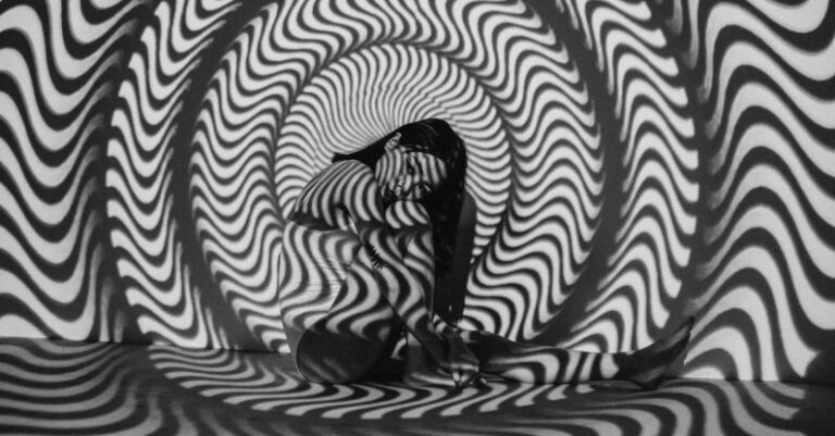 Optical Illusions - Woman Sitting Near Black and White Striped Wall