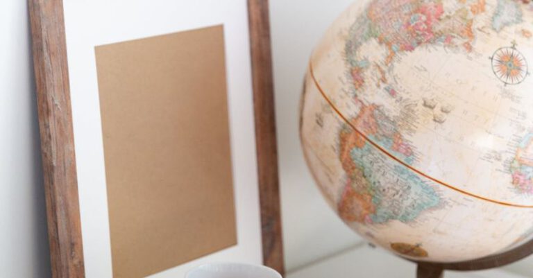 Promote - Vintage globe near blank frame and cup of tea placed on book in office