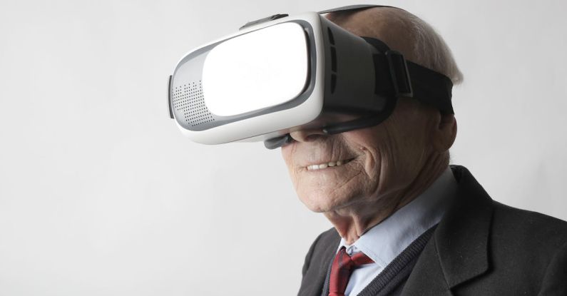 Interactive Exhibits - Smiling elderly gentleman wearing classy suit experiencing virtual reality while using modern headset on white background